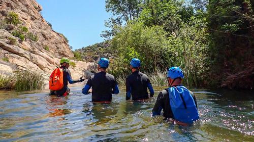 Escursionisti attraversano il fiume insieme alla guida