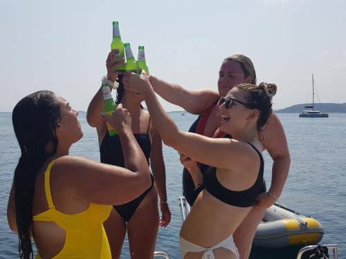 Girls aboard a boat make a toast with beer