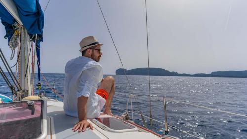 Junge auf einem Segelboot mit Blick auf Capo Caccia