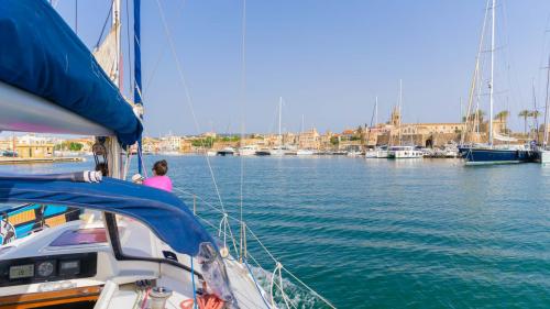 Segelboot läuft in den Hafen von Alghero ein und bietet einen Panoramablick auf die Stadt
