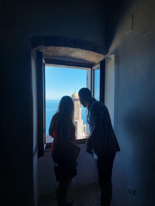 Blick aus einem Fenster auf den Glockenturm von Castelsardo