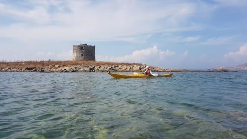 Tower in the coast of Alghero and hiker in a kayak