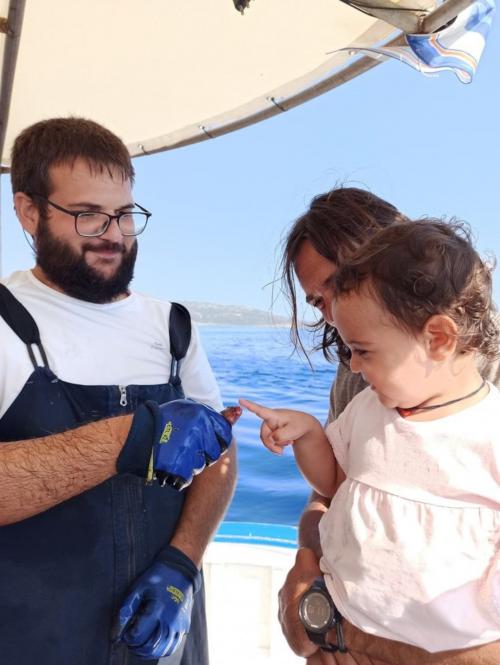 Petite fille touche un poisson fraîchement pêché