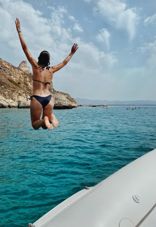 Girl in a black swimsuit jumps from the rubber dinghy