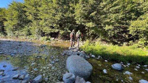 Two hikers cross the stream on the road to Gorropu