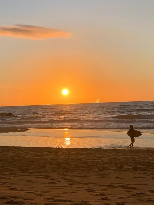 Junge mit Surfbrett bei Sonnenuntergang in Buggerru