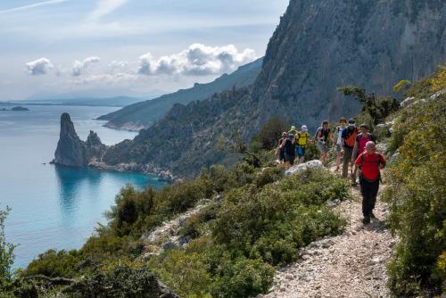 Escursionisti durante escursione di trekking e Guglia di Pedra Longa
