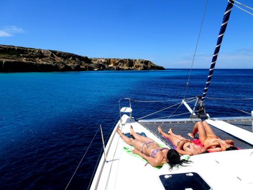 Mädchen sonnen sich an Bord eines Katamarans während eines Ausflugs im La Maddalena-Archipel