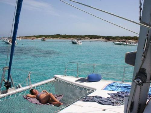 Girl sunbathing on lagoon catamaran in the clear waters of La Maddalena marine protected area